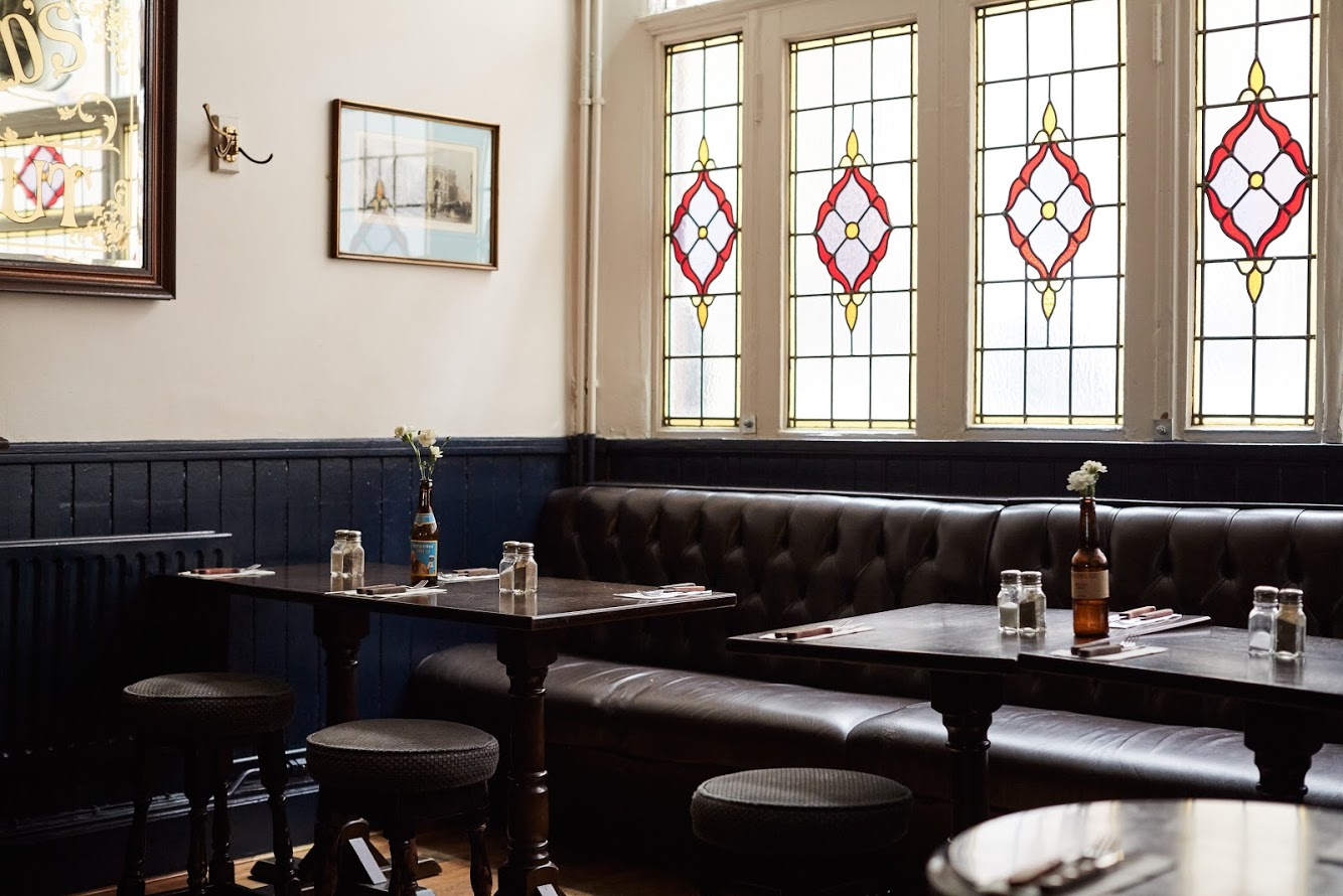 Leather banquettes beneath red and gold stained glass