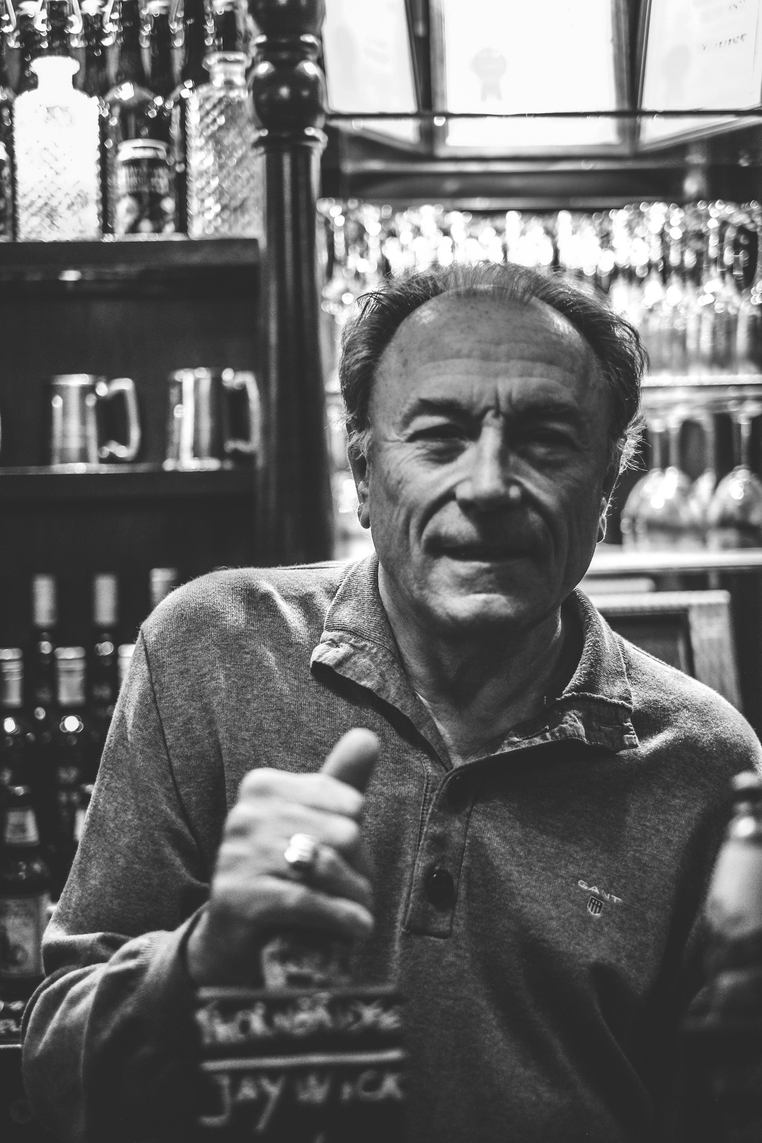A member of the house behind the bar, with tankards and glassware