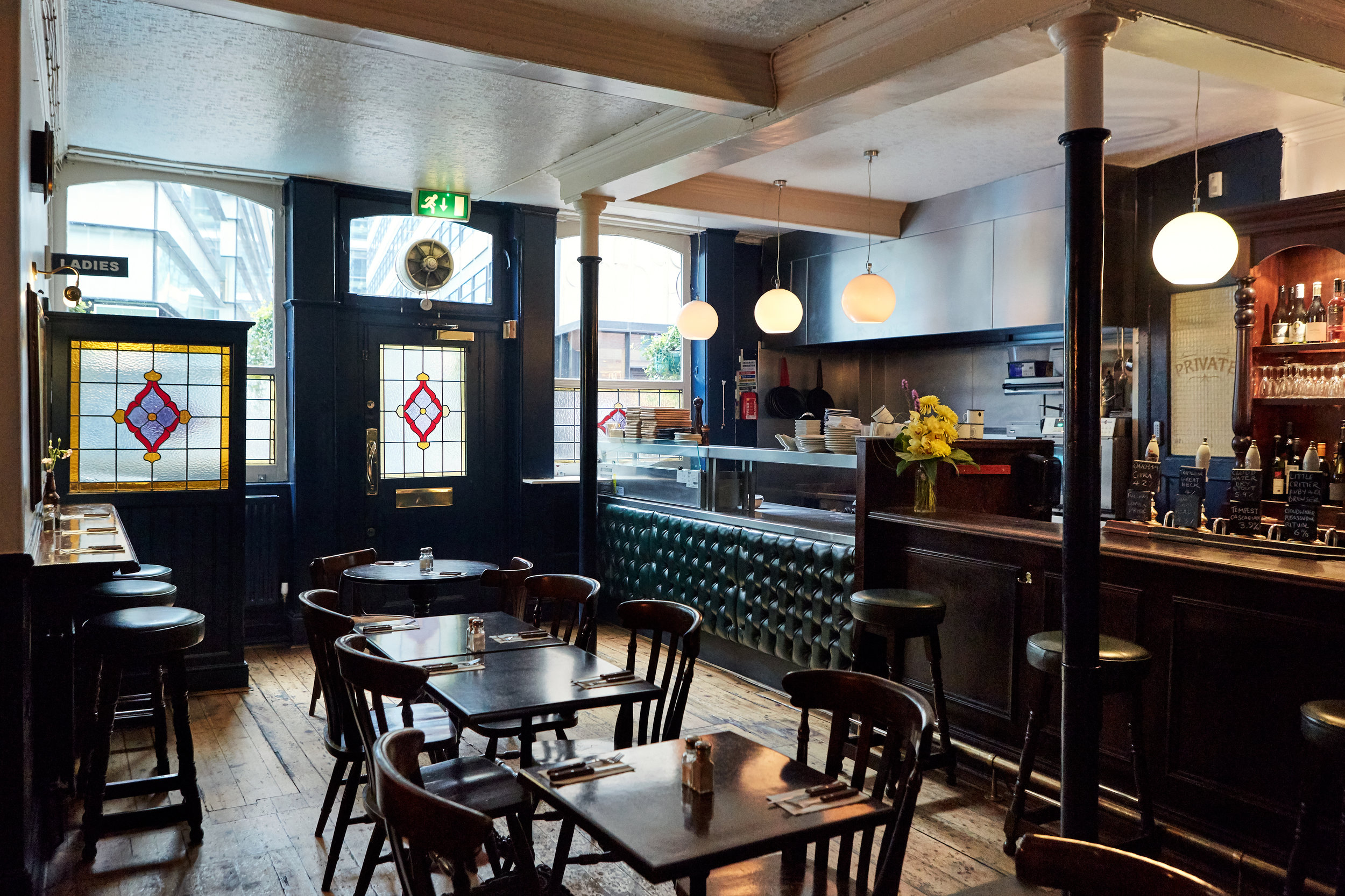 The dining room with stained glass, globe lights and a green leather banquette